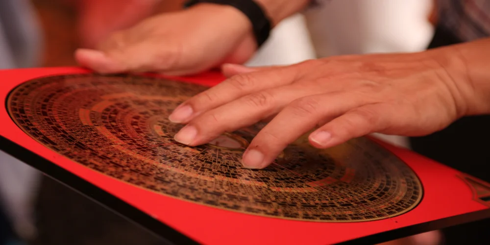 A feng shui master using a luo pan to take precise directional readings to map energy flow