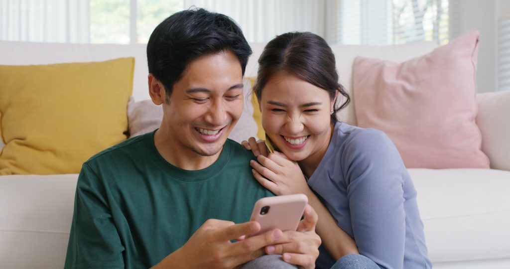 A happy couple looking at their phone, probably their savings account