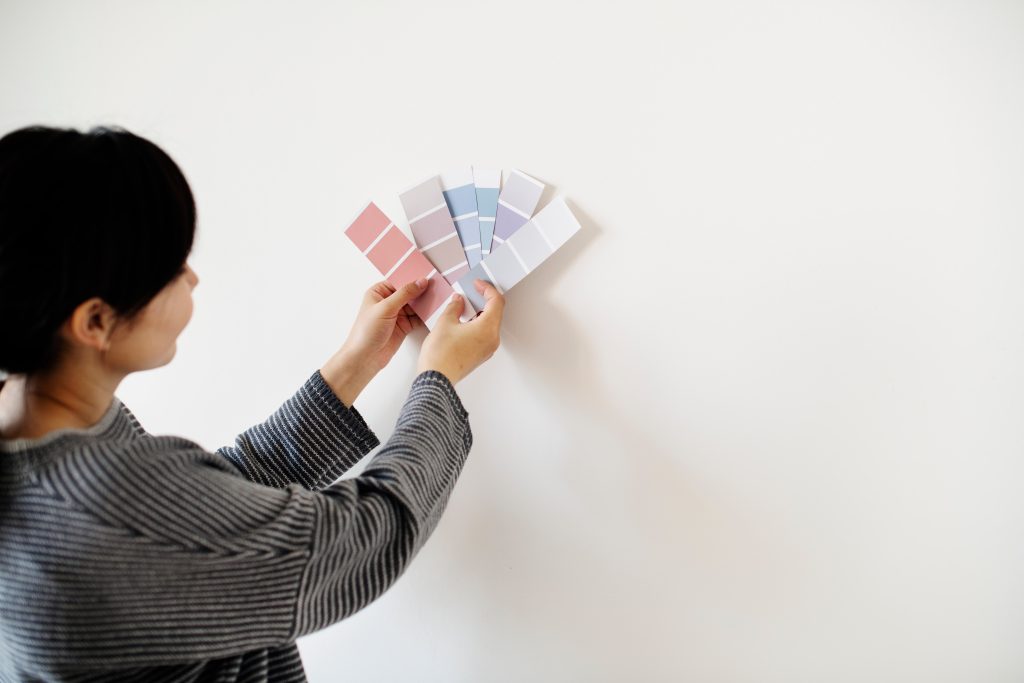 A lady placing color palettes against her wall to assess the best colour