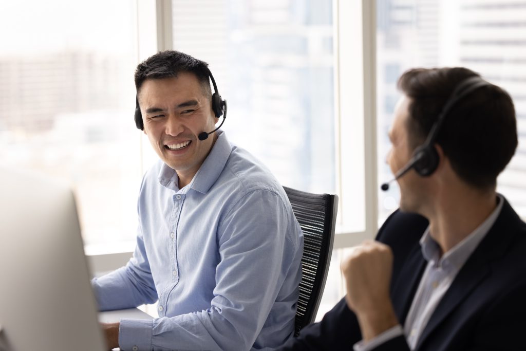 Two men in headphones laughing with each other in the workplace